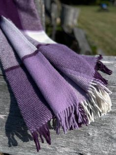 a purple and white blanket sitting on top of a wooden bench