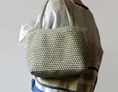 a woman carrying a crocheted bag with the word pattern on it's side