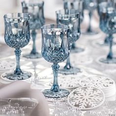 a table topped with lots of blue glass goblets and plates covered in snowflakes