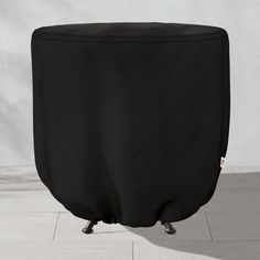 a black round ottoman sitting on top of a tile floor