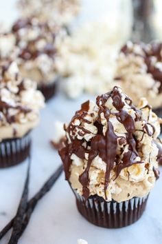 cupcakes with chocolate and marshmallow toppings on a white tablecloth