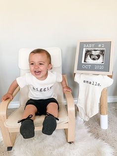 a baby sitting in a wooden chair next to a sign