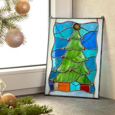 a stained glass christmas tree is on the window sill