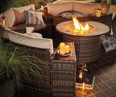 a fire pit sitting on top of a patio next to some chairs and tables with candles