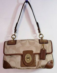 COACH Peyton Signature Beige Satin Leather Trim Turn Lock Shoulder Bag #14504. Khaki fabric Brown leather Brick orange satin fabric within Lots of compartments Turnlock Flap closure Zipper pouch at the back and within (L) 11.5 x (H) 7 x (W) 3 inches Strap 17 in 2000s Stuff, Orange Satin, Pretty Bags, Leather Trim, Michael Kors Monogram, Satin Fabric, Zipper Pouch, Leather Trims, Brown Leather