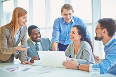 a group of business people sitting around a table with a laptop in front of them