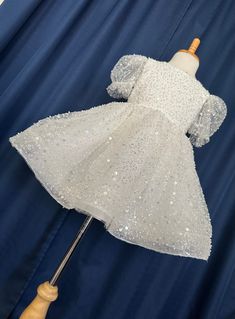 a white dress with sequins on it is being held by a wooden dummy