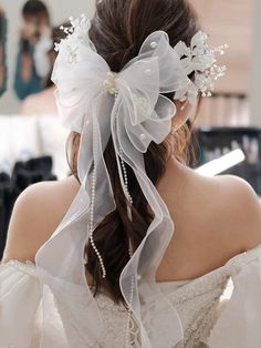 a woman wearing a veil with flowers in it's hair is seen from behind