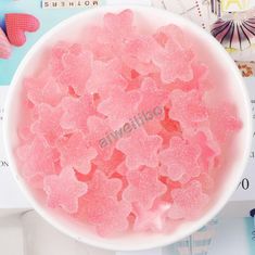 a bowl filled with pink sugar flakes on top of a white table next to other items