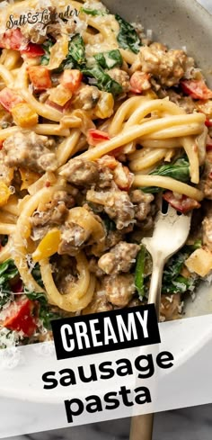 creamy sausage pasta with spinach and tomatoes in a white bowl