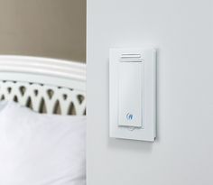 a white light switch mounted on the side of a wall next to a neatly made bed