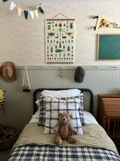 a teddy bear sitting on top of a bed in a room with wallpaper and decor