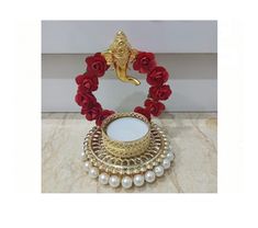 a gold plate with red roses and pearls around it on a marble countertop next to a mirror