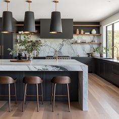 a kitchen with marble counter tops and wooden stools next to an island in the middle