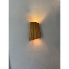 a wall light that is on the side of a white wall with a wooden lamp shade