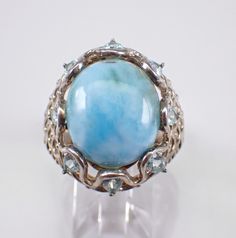 Vintage Sterling Silver Larimar and Blue Topaz ring. This ring is set with an Oval Larimar Cabochon Gemstone in the center and eight Pear shaped Blue Topaz around.  The center gem measures 16 X 13 mm and the Blue Topaz measure 4 X 3 mm each. This ring is finger size 9 and weighs 8.8 grams.  This ring measures 23 mm along the finger and sits 11 mm off the finger (height). This ring will be shipped promptly in a gift pouch. Oval Aquamarine Multi-stone Rings, Oval Multi-stone Aquamarine Ring, Oval Multi-stone Blue Topaz Gemstones, Oval Blue Topaz Multi-stone Gemstones, Oval Larimar Jewelry For Anniversary, Blue Topaz Rings With Stones, Unique Larimar Jewelry For Anniversary, Oval Larimar Gemstone Rings, Oval Moonstone Larimar Ring