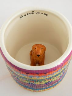 there is a small toy bear in the bottom of a cup that says life is better with a dog