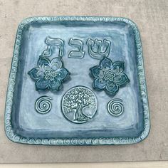 a blue tray with flowers and the word peace on it is shown in front of a concrete wall