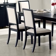 a dining room table and chairs with white upholstered backrests in black finish