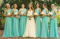 a group of women standing next to each other in front of some trees and bushes