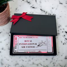 a black box with a red bow on it next to a small potted plant