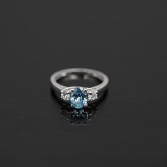 a blue and white diamond ring on a black surface