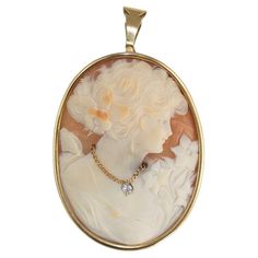 Vintage hand-carved shell cameo brooch/Pendant with thick 14k yellow gold bezel. The bezel tests 56.7% gold with an XRF metals analyzer. The gross weight of the cameo brooch is 20.2 grams. There is a small old-Euro cut diamond on the necklace of the figurine. Finely carved and polished cameo. The brooch measures 2 inches long and 1 1/2 inches wide. There is a bail attached to wear as a necklace and also a pin to wear as a brooch. Overall very good condition. Carved Shell, Cameo Brooch, Diamond Cuts, Hand Carved, Shells, Yellow Gold, Carving, Yellow, Pendant