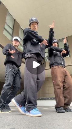 three young men standing next to each other in front of a building with their hands up