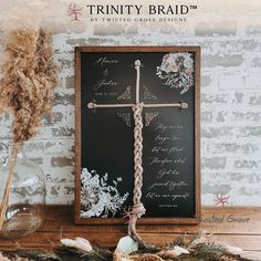 a wooden frame with a cross on it next to some feathers and other items in front of a brick wall