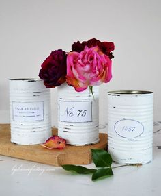 three vases with flowers in them sitting on a wooden board next to each other