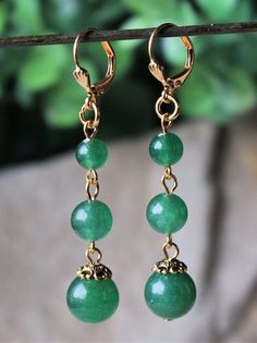 "This simple yet elegant pair of earrings features three emerald green jade gemstones. Hanging from a surgical steel lever-back, it measures 2.5\" in length. Earrings are light weight and sway gracefully as you move about your day. These beautiful dangle earrings are unique, feminine and eye-catching, a great accent to any wardrobe. Also available in sterling silver plate. Available with sculpted clip-on earrings top, please see last photo." Green Gemstone Round Bead Earrings, Green Gemstone Earrings With Round Beads, Elegant Green Jewelry With Lever Back Ear Wires, Green Jade Earrings For May Birthstone, Elegant Green Nickel-free Clip-on Earrings, Hypoallergenic Jade Drop Earrings, Elegant Green Round Clip-on Earrings, Elegant Nickel-free Green Jewelry, Elegant Round Aventurine Jewelry