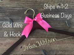 a pair of pink and brown clothes hangers with bows on them, labeled ships in 1 - 2 business days