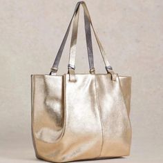 A tote bag that says: "I’ve arrived." Shimmery, all-over metallic detail for making a statement. And lots of space inside. Includes interior full-width & depth zip pocket and side slip pocket. 12" handle drop. Bag is 17"W x 12"H x 7"D Materials: Outer: 100% Leather. Inner: 100% Cotton Metallic Rectangular Travel Bag, Chic Metallic Shoulder Bag For Everyday Use, Metallic Tote Bag For Travel, Metallic Leather Shoulder Bag For Everyday, Metallic Travel Bag With Zipper Closure, Metallic Travel Tote Bag, Chic Metallic Bags For Everyday Use, Modern Gold Satchel With Handles, Chic Metallic Everyday Bag