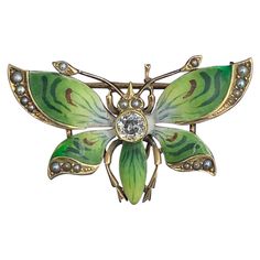 A wonderful and rare early Art Nouveau Brooch Pendant in the form of a Butterfly. The magnificent Butterfly is 14 Karat Gold. It is set with a central gorgeous Old Mine Cut Diamond of approximately .20 Carats. The diamond is just stunning - with the incredible sparkle of the antique diamonds that we love. The jewel is set with the most beautiful enamel in colors of green and black. The edges of the wings and the two antennae are set with seed pearls. The gem is a masterpiece of the Art Nouveau period. It dates to Circa 1880-1920. The butterfly can be worn as a brooch or as a pendant with a chain through the lower loop so it would hang down. The butterfly is 1 1/4 inches (33mm) wide and 3/4 inch (20mm) tall. The central diamond is on Old Mine Cut Diamond of approximately 0.20 Carats and 4mm Art Nouveau Cabochon Brooches For Weddings, Art Nouveau Cabochon Wedding Brooches, Victorian Enamel Brooches For Formal Wear, Victorian Enamel Brooches For Formal Occasions, Collectible Art Nouveau Hallmarked Brooch, Victorian Style Enamel Brooches For Formal Occasions, Antique Green Brooch For Evening, Antique Enamel Brooches For Formal Occasions, Green Art Nouveau Wedding Brooches