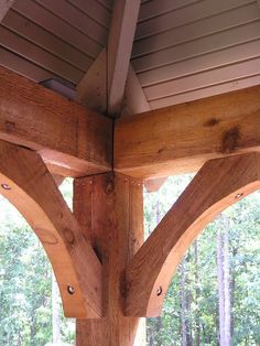 an outdoor covered area with wooden beams and wood flooring on the side of it