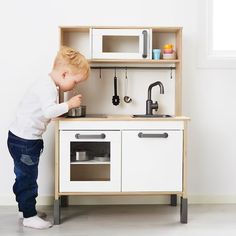 a little boy playing with a toy kitchen set