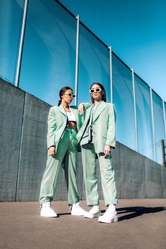 two women standing next to each other in front of a fence