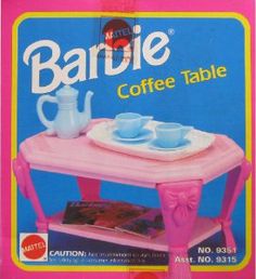 the barbie coffee table is pink and has two cups on it, one with saucers