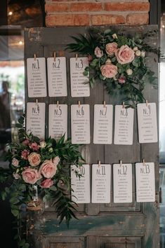 the seating chart is displayed on an old door with flowers and greenery around it