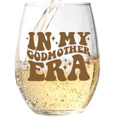 a wine glass filled with white liquid and the words in my godmother era