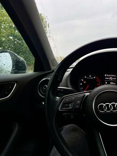 the interior of a car with dashboard lights and steering wheel view through rain - soaked windshield