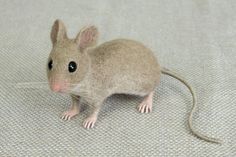 a toy mouse sitting on top of a white cloth covered floor with it's eyes wide open