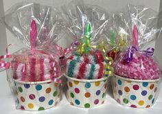 three cupcakes wrapped in plastic and decorated with bows