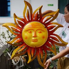 a woman standing next to a yellow and red sun decoration