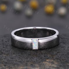 a white gold wedding band with an opal stone in the center