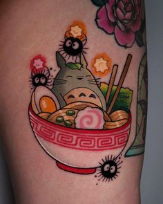 a cat in a bowl with chopsticks and sushi on the side of her leg