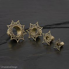 three pairs of earrings sitting on top of a black stone floor next to each other