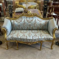 an ornately decorated couch sits in a room with other antique chairs and tables behind it