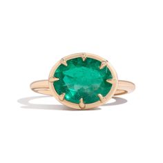 an oval emerald stone ring with gold trimmings on the band and a small round green