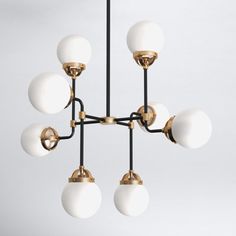 a chandelier with six white balls hanging from it's center and four gold arms